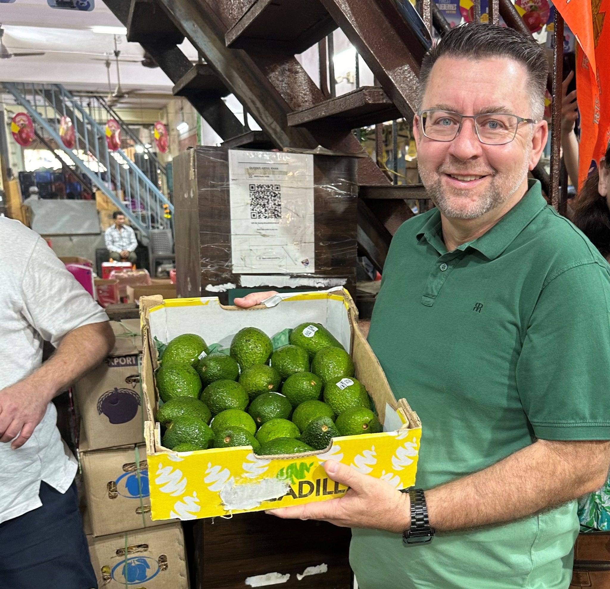 Man holding a box of avocados