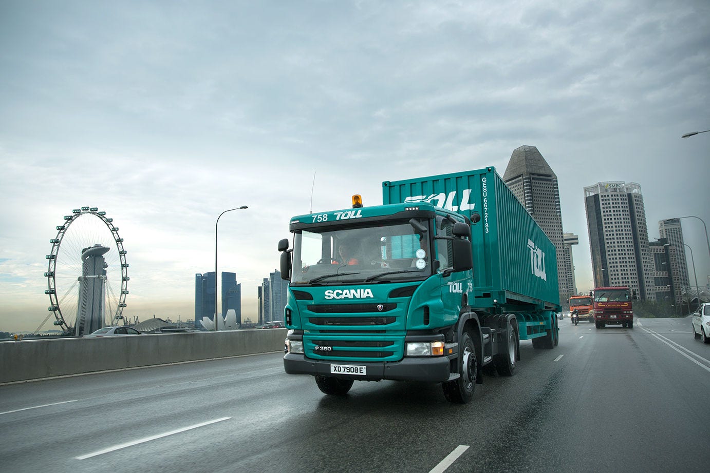 Toll truck on a road with a city skyline behind.