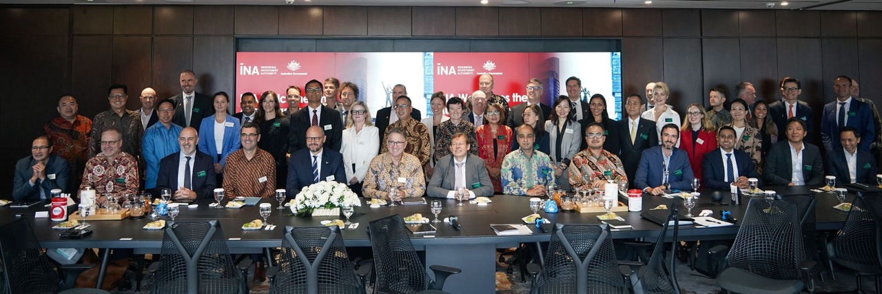 A group of business people sitting or standing behind a conference table.